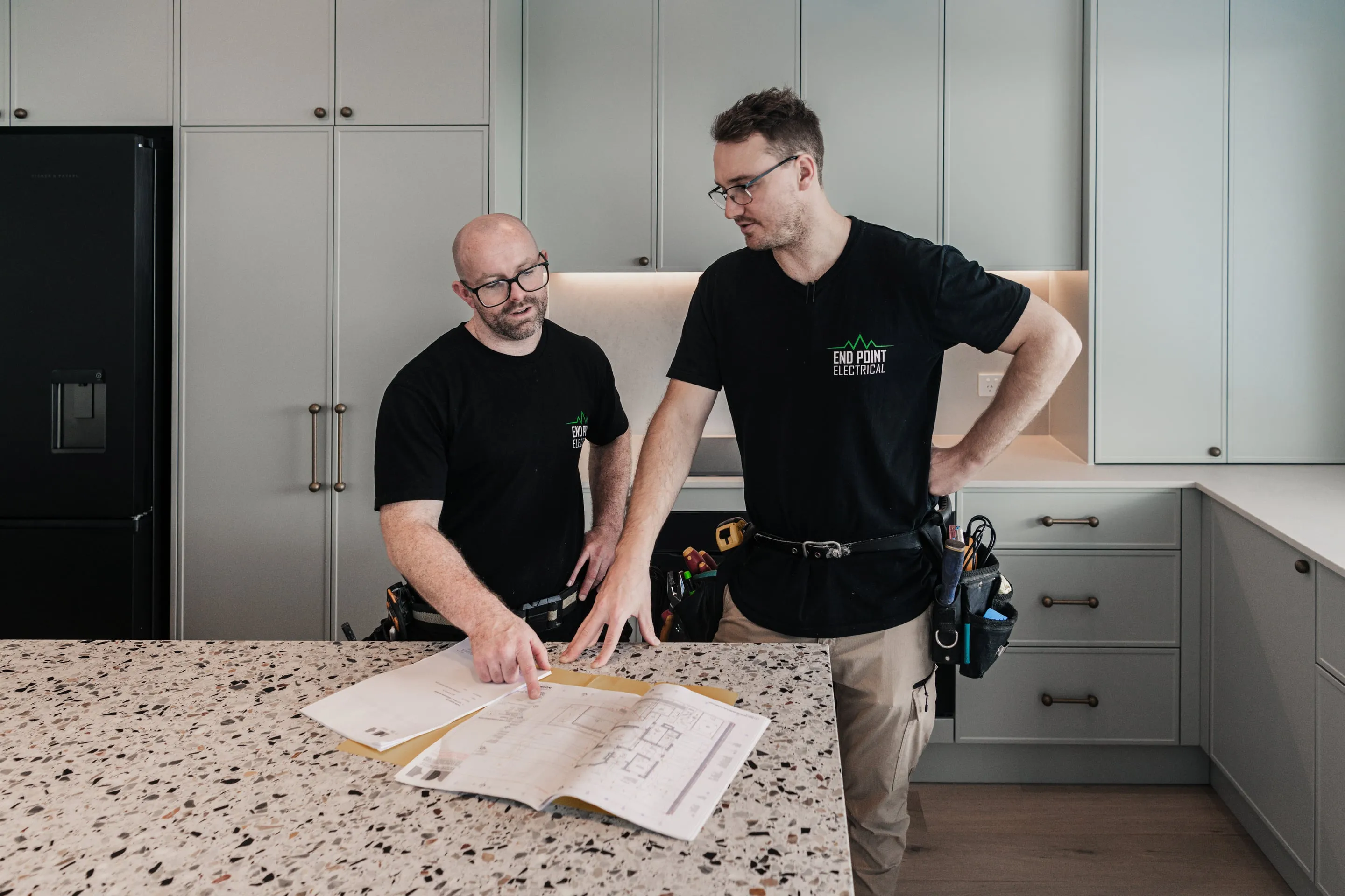 Two End Point electricians reviewing lighting and power plans on a kitchen bench at Collaroy