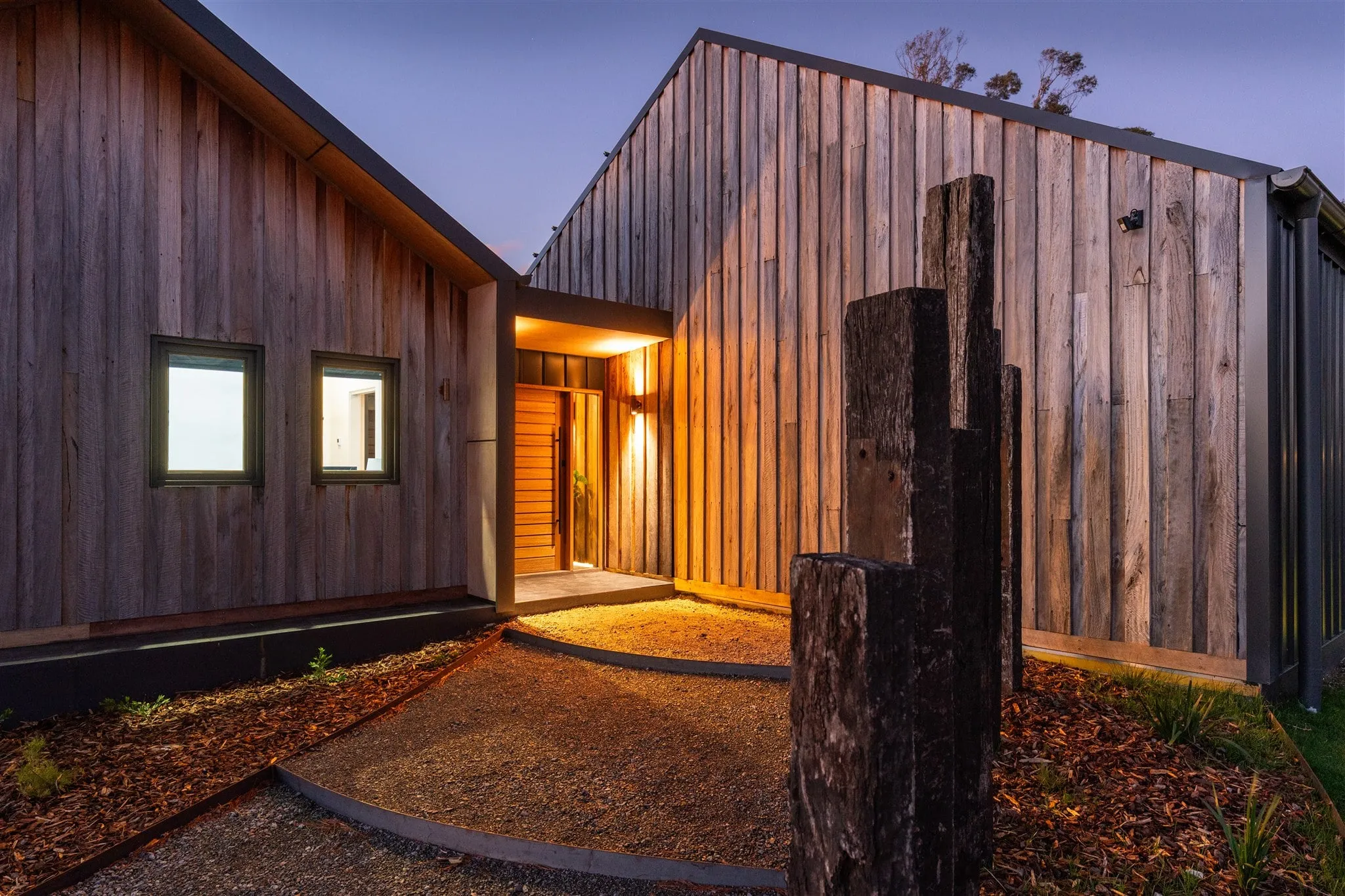 Timber-clad Wingello home at dusk with lit entry and exterior lighting