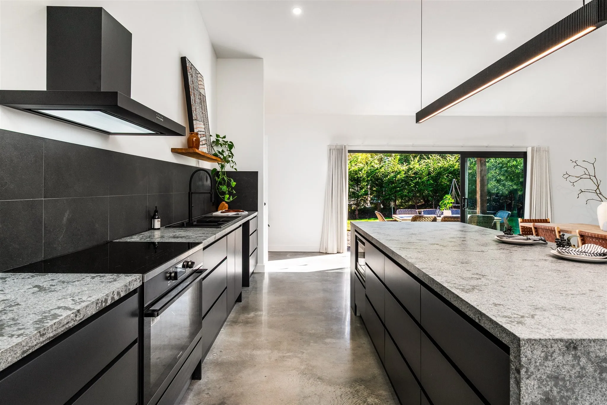 Wingello kitchen with pendant strip lighting over a stone island and polished concrete floors